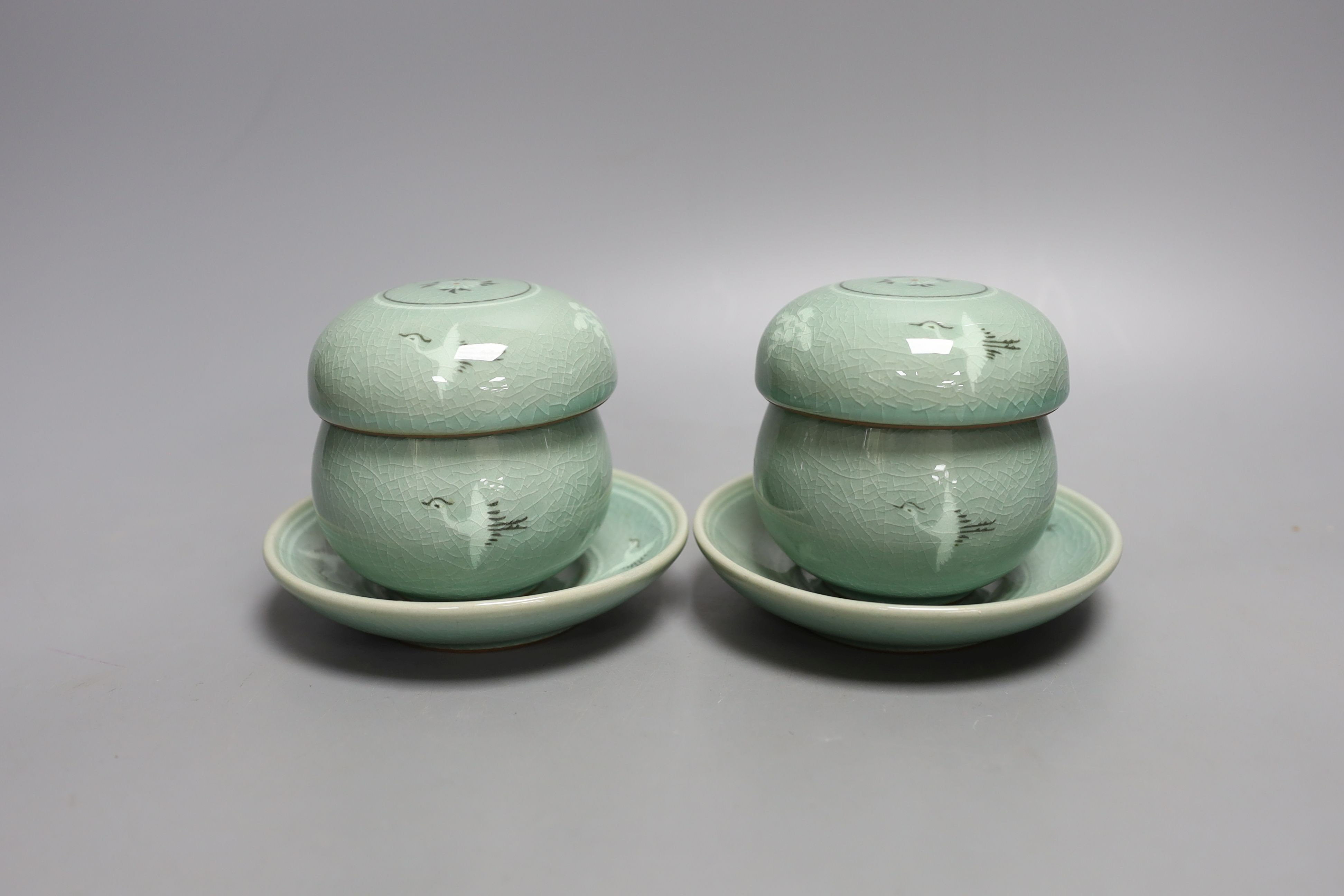 A pair of Korean green glazed pottery tea bowls, cover and stand with strainer each inside - 11cm tall